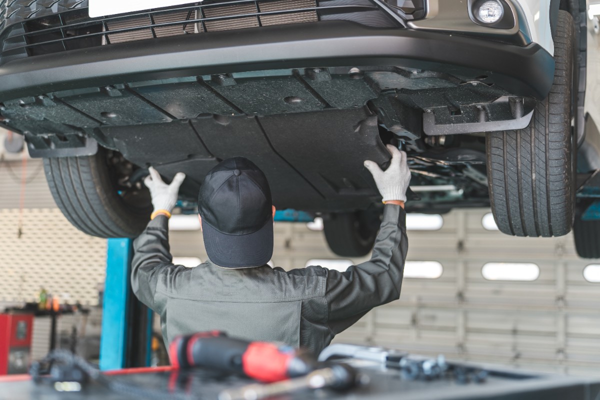 リフトされた車を整備する整備士