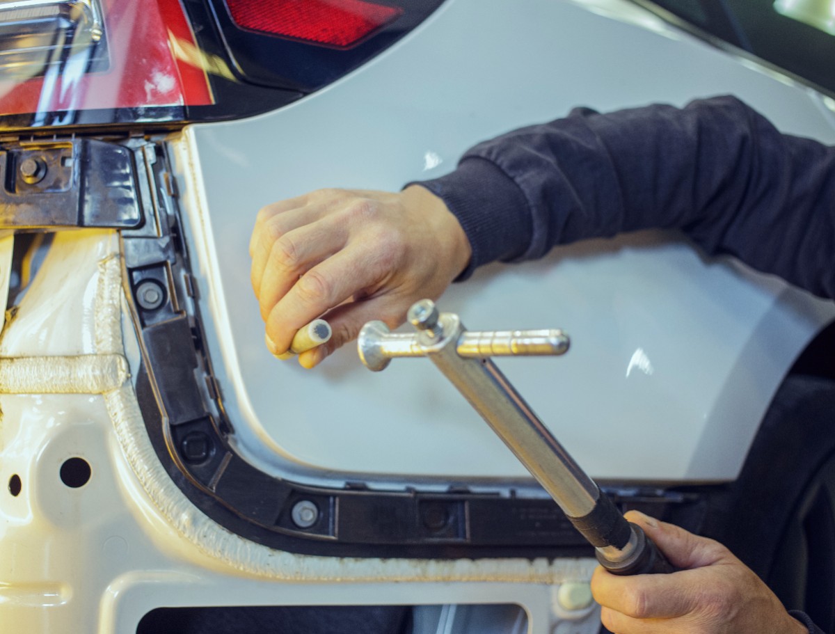 車のトランク部分で金属製工具を使った修理作業