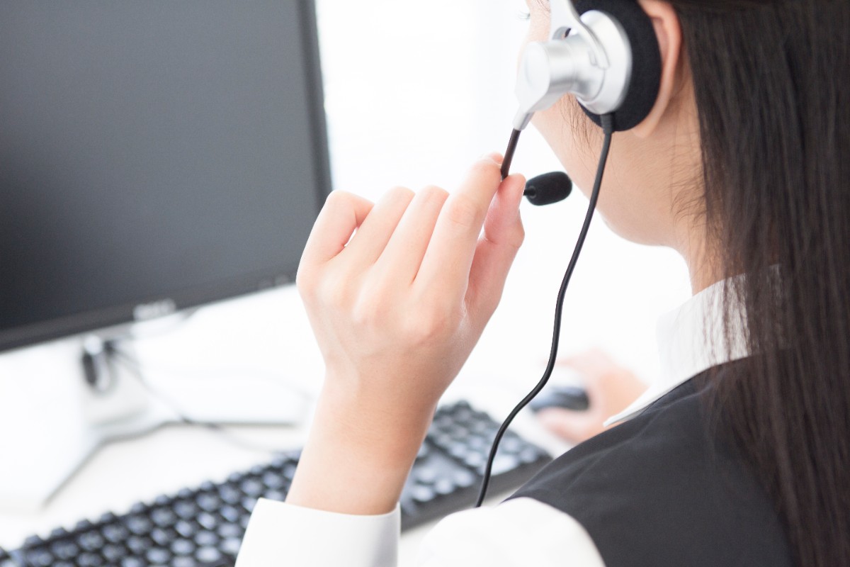 ヘッドセットを着けてオフィスで電話対応する女性