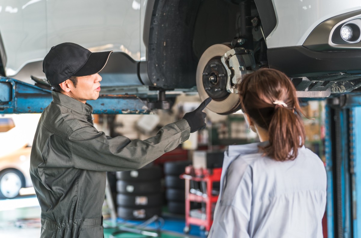 自動車整備工場でメカニックが顧客に車の状態を説明している様子