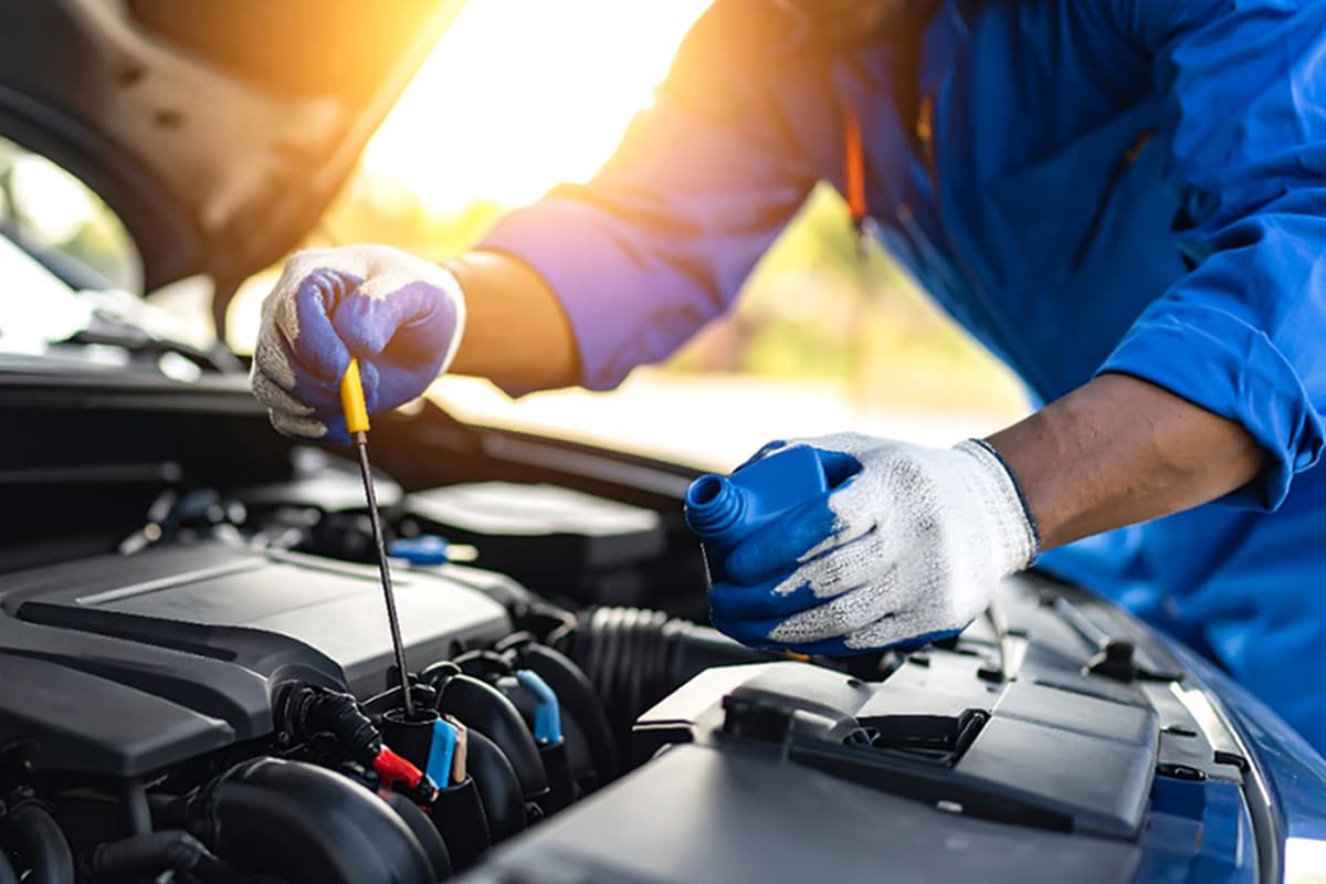 自動車整備工場でエンジンオイルを補充する作業員