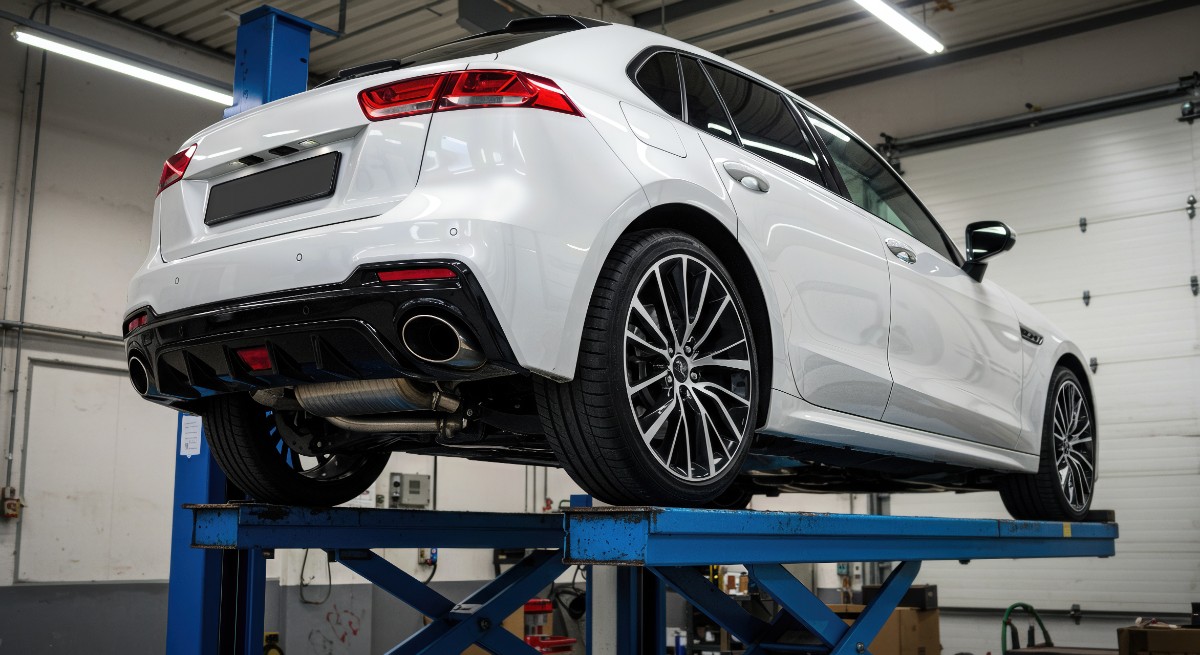 自動車整備工場でリフトアップされた白いセダン車